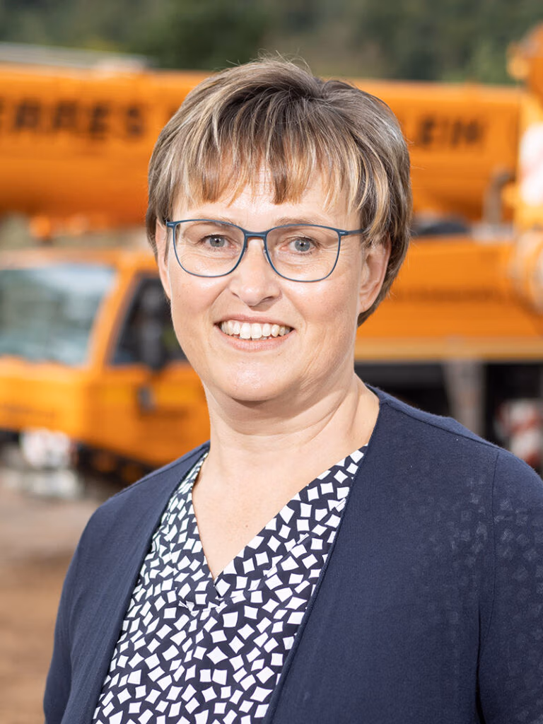 Porträt von Juanita Schwaab, Bauingenieurin bei Berres Kranverleih, aufgenommen vor einem gelben Mobilkran auf dem Firmengelände.